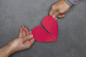 two people tearing paper red heart in half