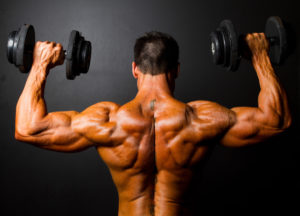 rear view of bodybuilder training with dumbbells on black background