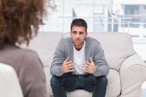 man on therapy couch talking to female