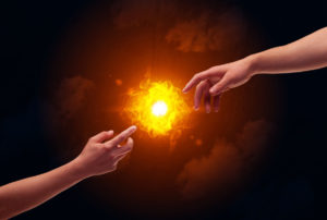 Two naked male hands about to touch, lighting a bright flame with smoke in red sky background concept
