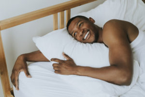 smiling black man in bed deposit photo April 2020
