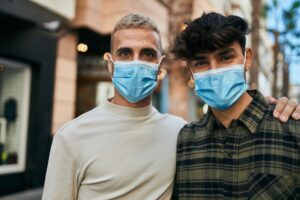 young gay couple wearing masks