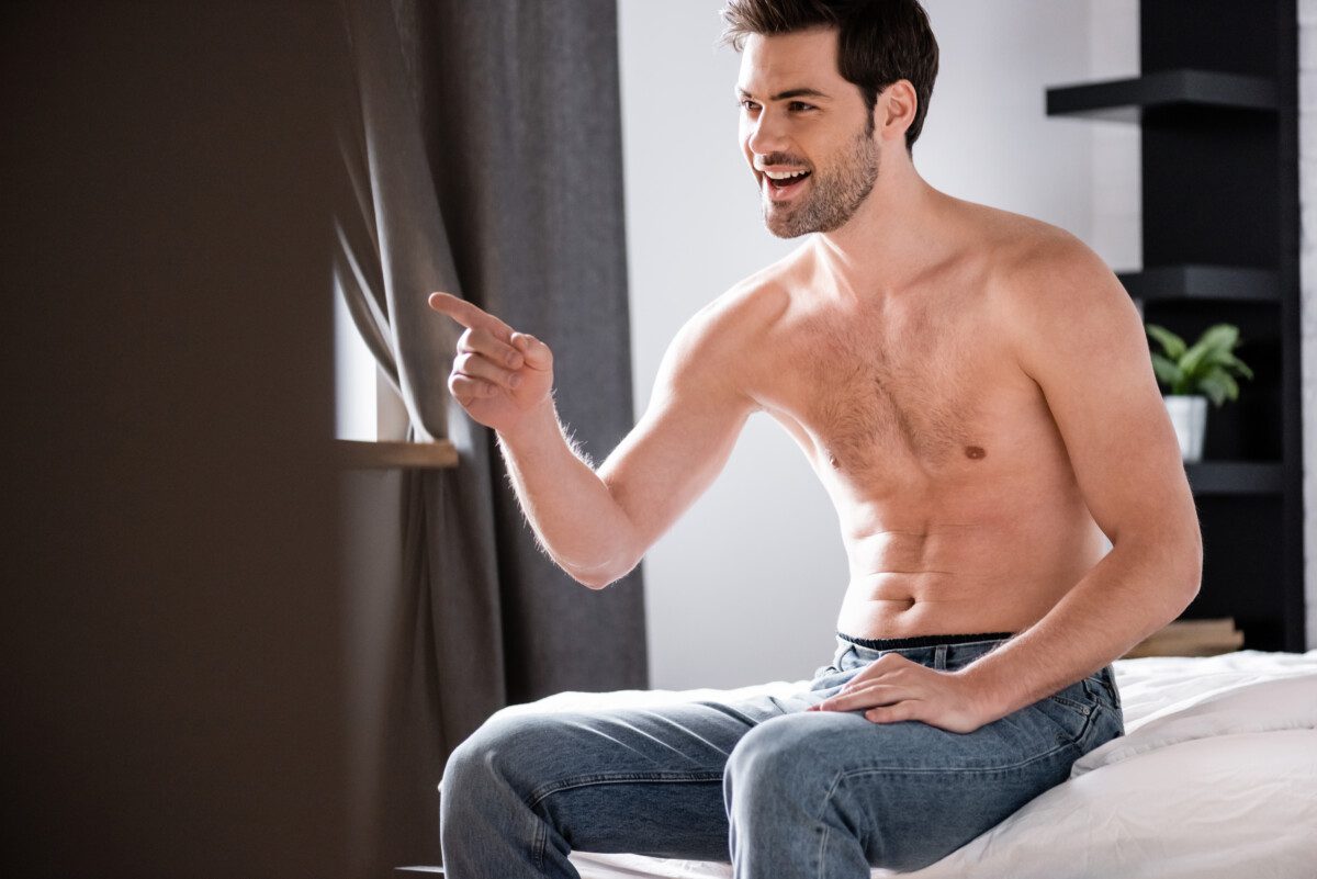 shirtless man pointing sits on bed deposit photo 2 8 21