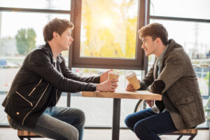 two men talking over coffee at a table deposit photo April 2021