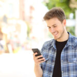 young gay man lookin at iphone deposit photo July 2021
