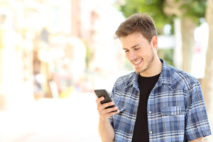 young gay man lookin at iphone deposit photo July 2021