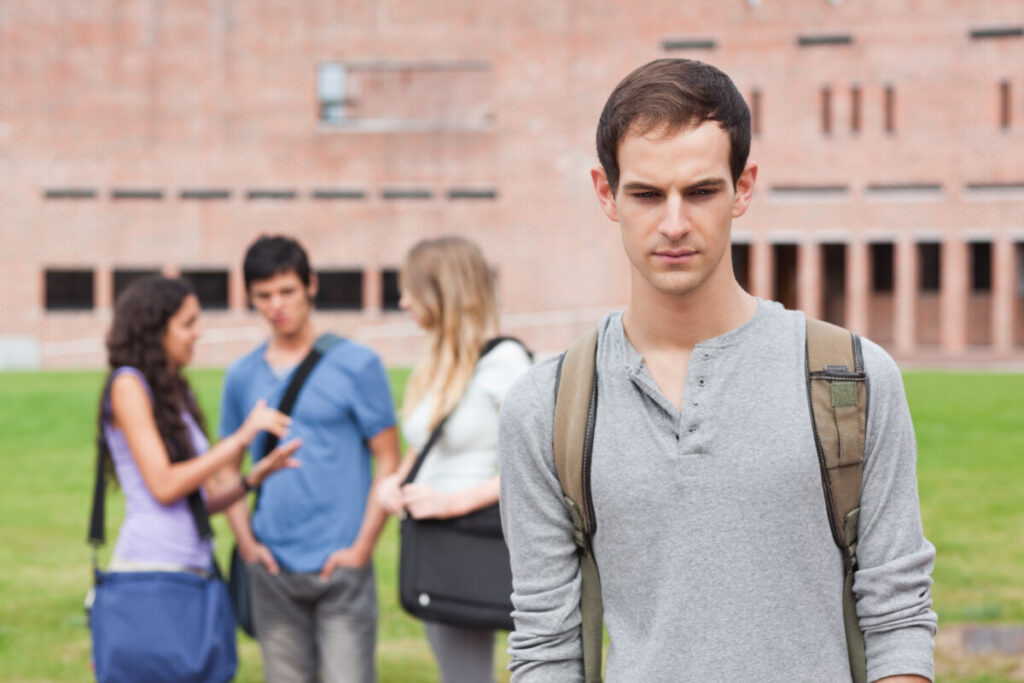 lonely man on college campus as others talk deposit photo September 2021