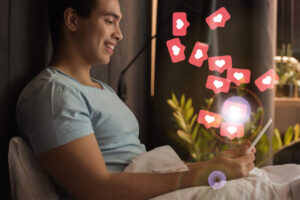 man with phone in bed and heart emojis deposit photo december 2021