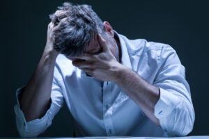 man with face in hands blue shirt deposit photo 3 29 22