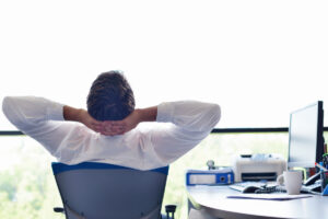 man alone at office with arms up back to us June 2022