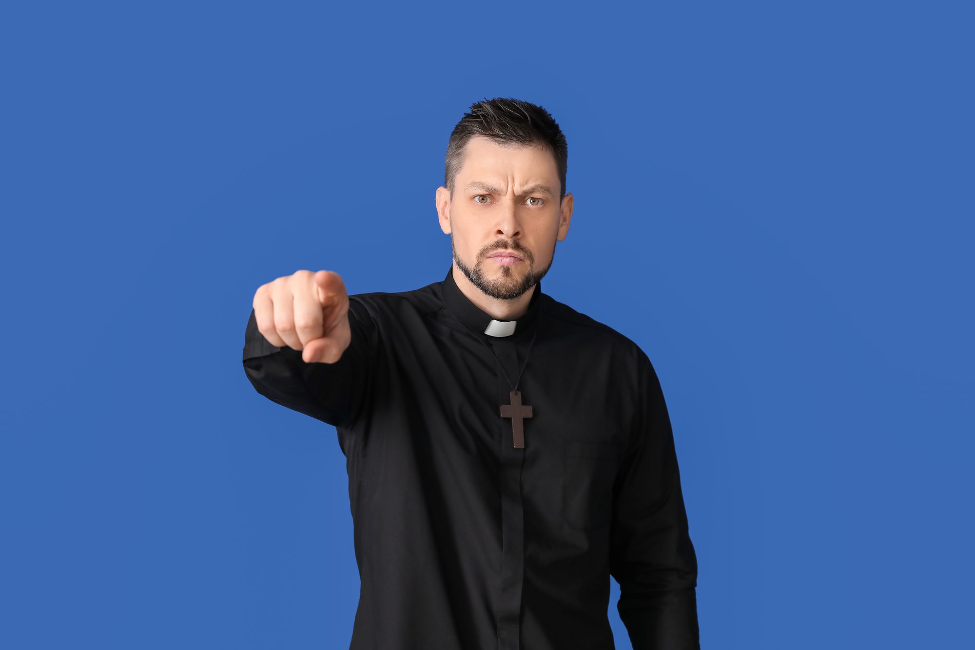 Angry priest pointing at viewer on color background - Gay Therapy LA