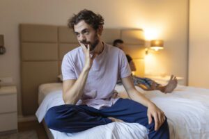 Frustrated sad boyfriend sit on bed think of relationship problems, thoughtful gay couple after quarrel lost in thoughts, upset lovers consider break up, offended person disappointed by boyfriend