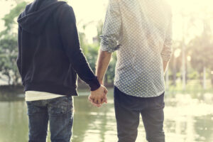 Gay couple walking together holding hands, representing emotional safety, trust, and lasting intimacy.