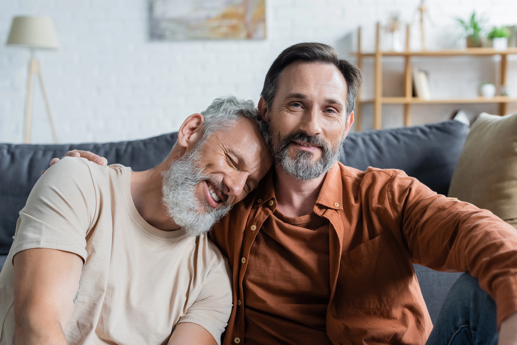 Mature gay couple embracing at home in a long-term relationship.